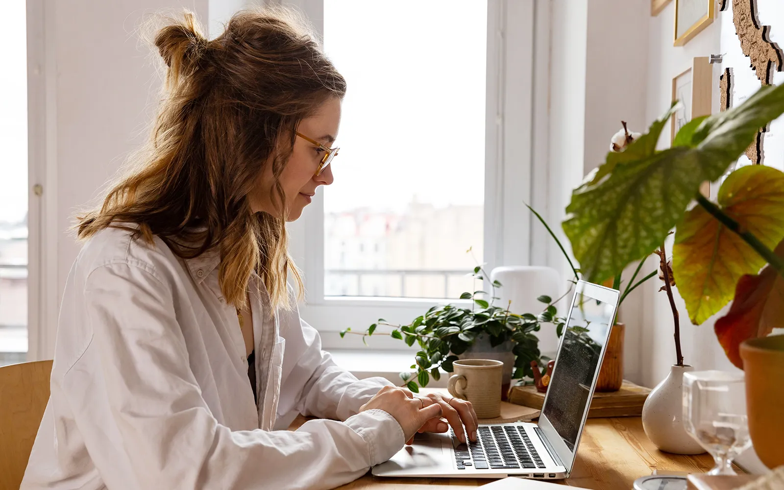 A woman at a desk works on a laptop.